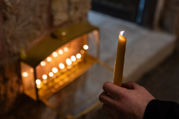 An Orthodox, haredi, Jewish man holds a long, wax, yellow taper candle as he recites the blessing...