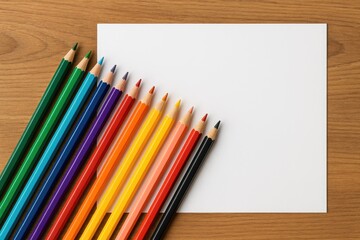 Obraz premium Vibrant colored pencils arranged on a wooden surface with paper seen from above