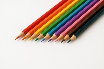 Fototapeta premium Colored pencil crayons arranged on a white surface for school supplies.