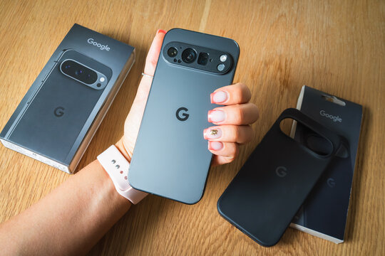 Tallinn, Estonia - July 7, 2025: A woman unboxes the new Google Pixel smartphone at a table, showing the back panel and camera.
