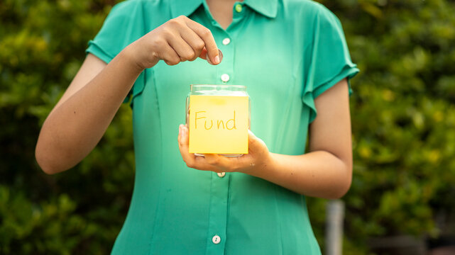 Person Donating Change to a Fund Jar Outside