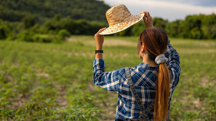 Woman Adjusts Straw Hat in Green Field
