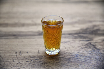 Bottle and glass of moonshine or vodka on black wooden
