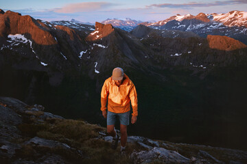 Man hiker traveling in Norway hiking in sunset mountains active adventure trip, traveler climbing...