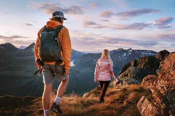 Couple friends hiking in sunset mountains travel in Norway, hikers group man and woman backpacking...
