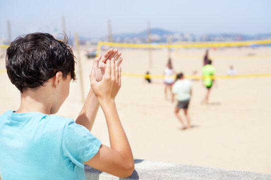 teenage boy watching beach volleyball game in summer