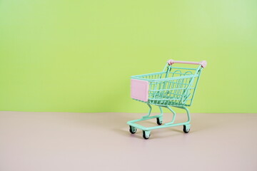 Mini Trolley shopping cart with space for text on pink and green background
