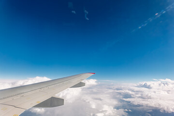 Obraz premium View from the airplane window at a beautiful cloudy sky and the airplane wing