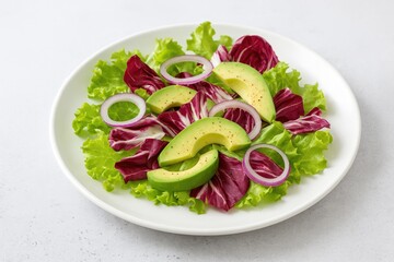 Fresh and healthy vegetarian salad featuring crisp greens, purple radicchio, sliced red onion, and creamy avocado served on a white dish with a concrete background