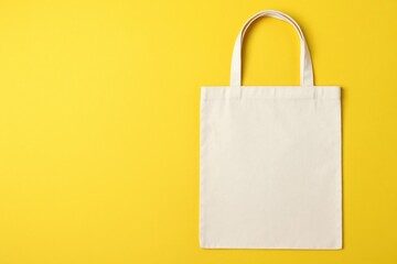 Eco-friendly cotton bag displayed from above on a yellow backdrop with space for customization