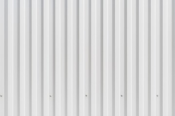 Horizontal to vertical striped view of a corrugated metal sheet used as a fence