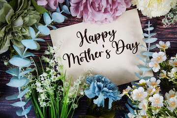 Happy Mother's Day text with flowers bouquet decoration on wooden background