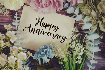 Happy Anniversarytext with flowers bouquet decoration on wooden background