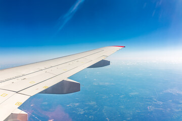 View from the airplane window at a beautiful blue clear sky and the airplane wing