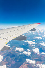 Obraz premium View from the airplane window at a beautiful cloudy sky and the airplane wing
