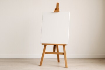 Wooden artist's stand holding an empty canvas against a softly lit wall