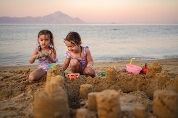 Joyful children building sandcastles at sunset on a tranquil beach