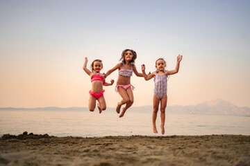 Joyful children jumping at sunset on a sandy beach