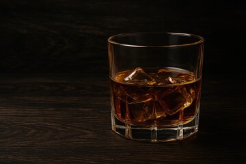 A whiskey glass set against a rugged dark wooden surface