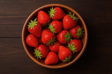 Close-up of fresh strawberries in a wooden dish against a dark wooden surface, viewed from above