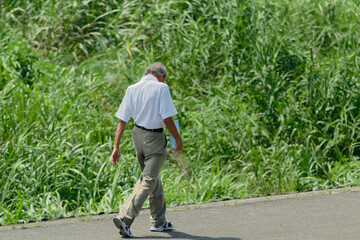 Elderly Japanese man walking riverbank