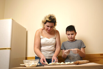 A boy and his mother are making puff pastry pies with apple filling. Home cooking.