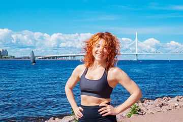 Portrait of smiling red-haired curly young woman in sportswear.
