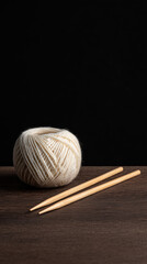 Yarn ball and knitting needles rest on a wooden surface. Crafting and knitting concept