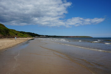 Sandy beach and coastal cliffs with gentle waves at Filey, North Yorkshire, England. Serene ocean view in a picturesque coastal town.