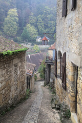 Charming cobblestone path leading to a historic house in Beynac-et-Cazenac, France under overcast...