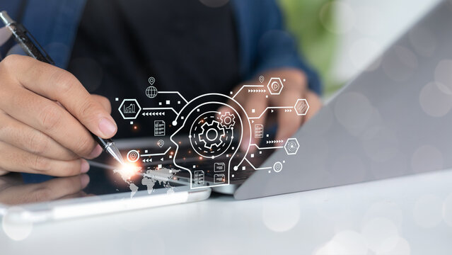 Close-up of a hand using a digital tablet and stylus with artificial intelligence, automation process, and business innovation icons, representing AI technology and digital transformation.