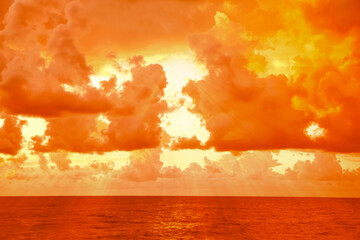Orange sky with clouds above sea during hot summer weather