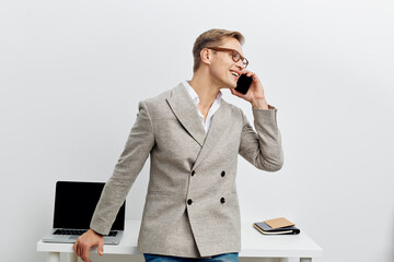 smiling man talking smartphone workspace laptop white background business casual communication...