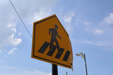Pedestrian Crossing Warning Sign Against Blue Sky Background