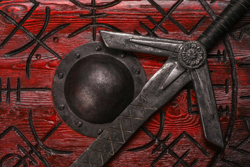 Old long medieval two handed knight warrior sword and viking wooden shield with ancient runes on...