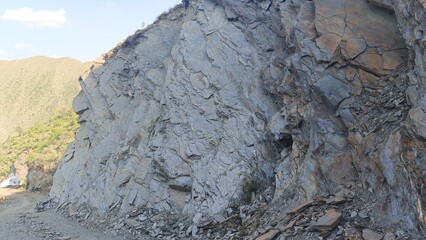 Dramatic Mountainside Rock Face, Rugged Texture, Grey and Brown Hues, Natural Landscape, Daytime Sunlight