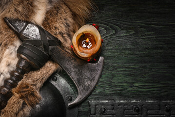 Medieval Viking axe and warrior wooden green black shied on old warrior table close up background. © Dmitriy