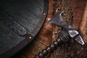 Medieval Viking axe and warrior wooden green black shied on old warrior table close up background.
