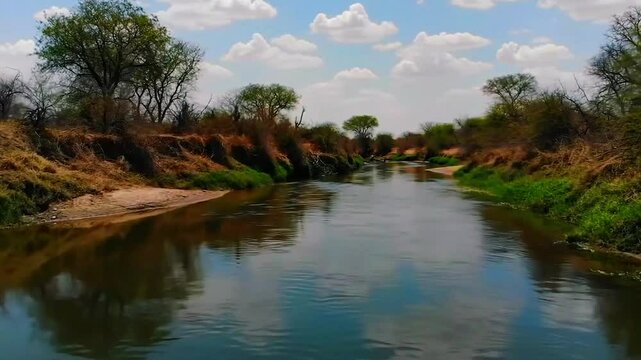Sungai jalur kuno di daerah semi-arid, vegetasi savana, air mengalir, Realistis, 3D look (cinematic), Statis (kamera diam), Smooth (gerakan tidak tersendat), 4K resolusi, Loopable seamless