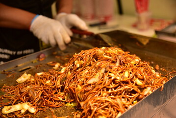 A street vendor is making teppanyaki fried noodles at night.
