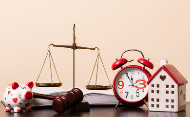 A judge's gavel, an open book, golden scales of justice and a symbolic miniature house