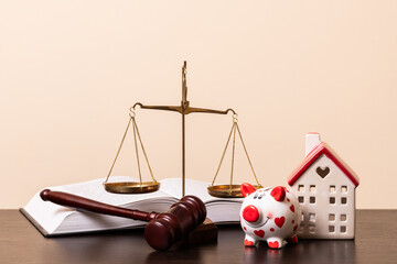 A judge's gavel, an open book, golden scales of justice and a symbolic miniature house