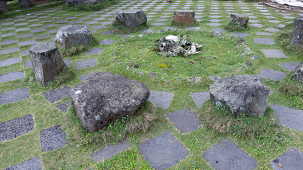 This image depicts an outdoor arrangement of large, weathered stones forming a circular pattern on...
