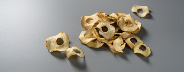 Dehydrated apple slices scattered across a smooth gray surface invite exploration of flavor and...