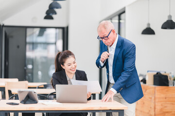 Young Asian businesswoman and senior Caucasian businessman working together in modern office,...