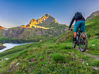 Cyclist riding electric mountain bike in pyrenees mountains at sunrise.