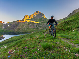 Cyclist riding electric mountain bike in pyrenees mountains at sunrise.