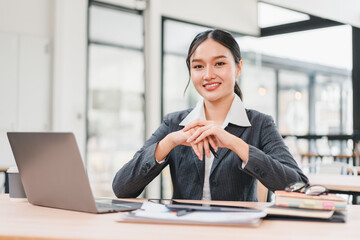 Confident businesswoman in formal suit working at desk with laptop, analyzing financial charts, and...