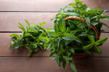 Freshly harvested mint in a rustic basket on a wooden table, symbolizing nature's bounty and culinary delight