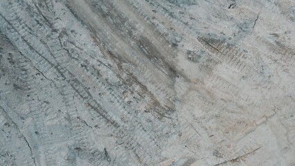 Top down view of dry cracked ground with visible tire tracks, showing drought-affected soil and...